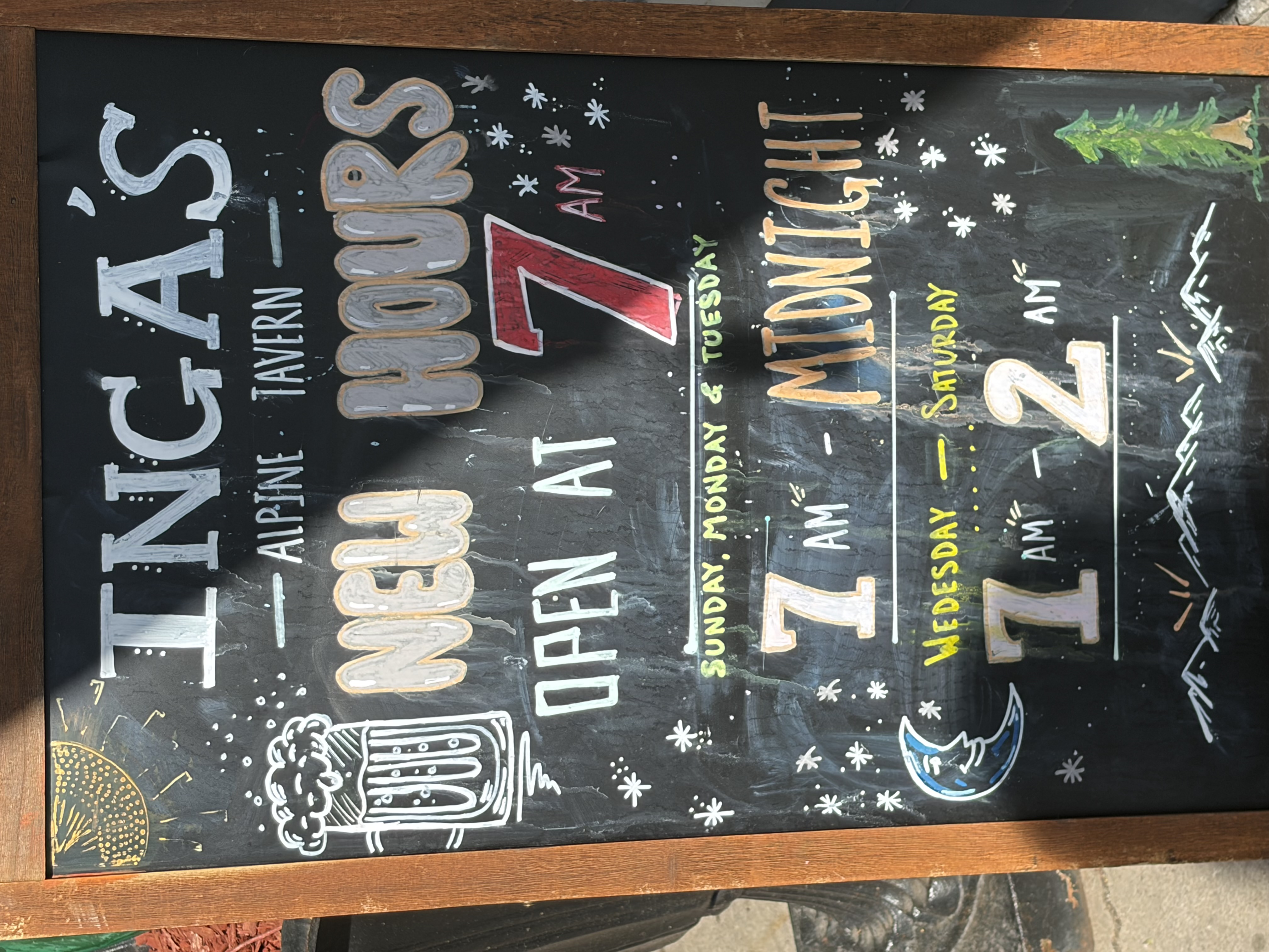 Chalkboard reading INGA'S ALPINE TAVERN NEW HOURS, OPEN AT 7 AM